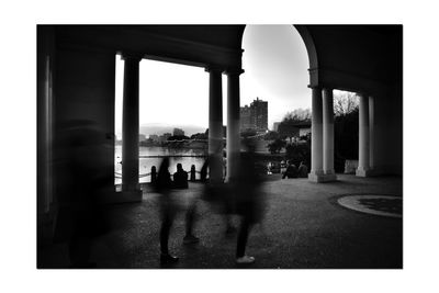 Silhouette people walking on road amidst buildings in city