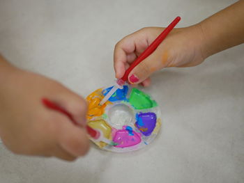 Baby's hand putting paint brush into the color tray getting ready to do painting