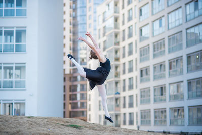 Woman jumping in front of building