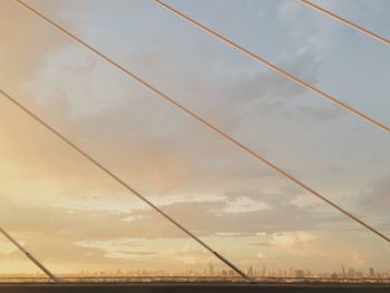 Low angle view of electricity pylon against cloudy sky