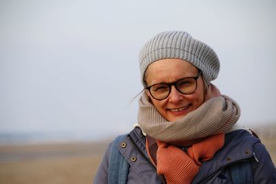 Portrait of young woman wearing hat against sky in beach