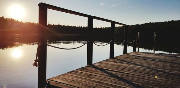 Pier over lake against sky during sunset