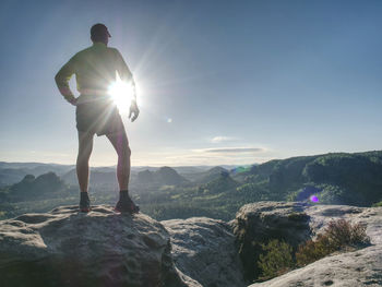 Man doing stretching exercise outdoors. extreme runner climbs the mountain top and see wide valley