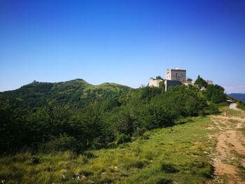 Built structure on landscape against clear blue sky