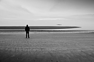 Rear view of man standing alone on beach