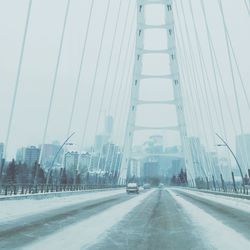 Road by bridge in city against sky