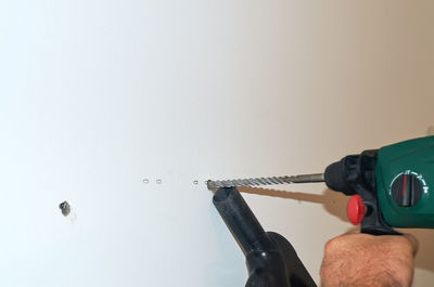 Man holding umbrella against wall