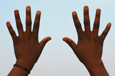 Close-up of hand showing stop gesture against clear sky