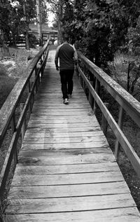 Rear view of man walking on footbridge