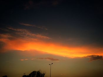 Low angle view of silhouette trees against dramatic sky