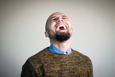 Close-up of man laughing against wall