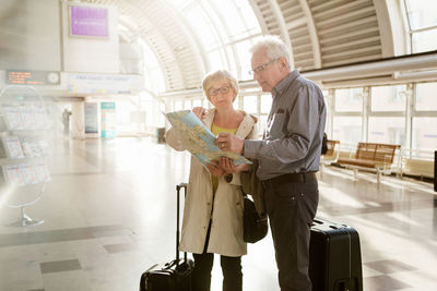 Senior woman pointing at map while standing with man on station