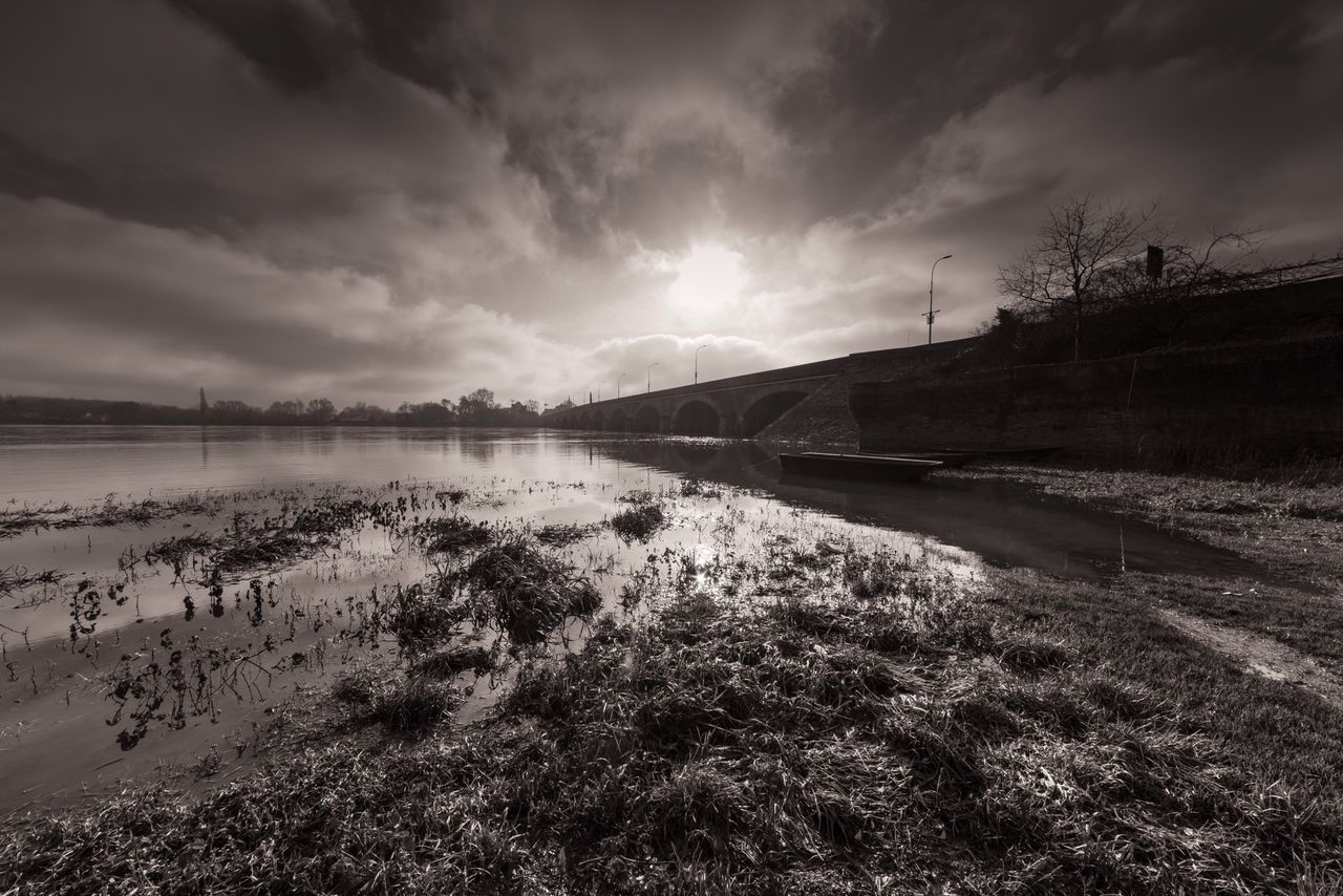 sky, water, cloud - sky, tranquil scene, tranquility, reflection, scenics, lake, nature, cloudy, beauty in nature, cloud, grass, river, sunlight, sun, landscape, outdoors, no people, idyllic