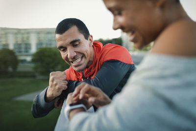 Man celebrating victory while woman checking time on smart watch