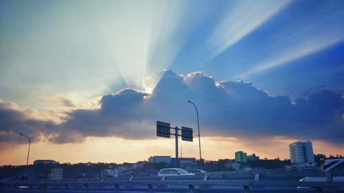 Street amidst buildings against sky at sunset