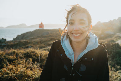 Portrait of young woman standing against mountain