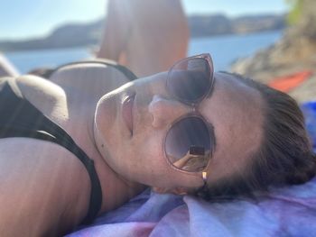 Close-up of woman wearing sunglasses lying on beach