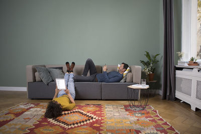 Couple relaxing together in the living room with different electronic devices
