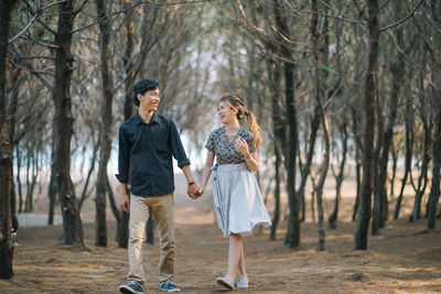 Smiling couple holding hands among dry branches