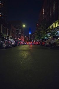 Cars on road by illuminated buildings in city at night