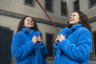 Smiling young woman standing against wall