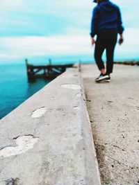 Rear view of man walking on pier over sea