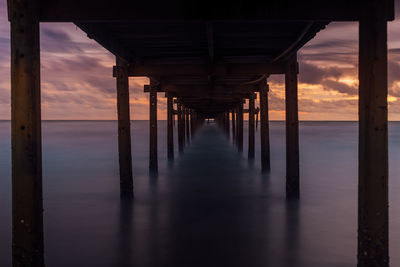 Pier over sea against sky during sunset