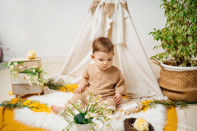 Baby playing at home on the floor tent and flowers spring