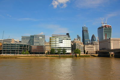 City at waterfront against blue sky