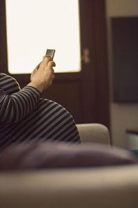 Midsection of man using mobile phone at home