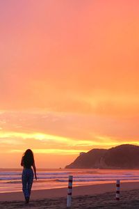 Rear view of silhouette people sitting on sea during sunset