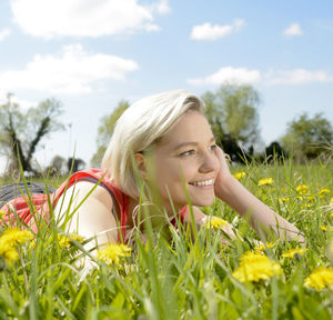 Smiling young woman looking away while lying on grass