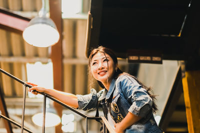 Smiling woman standing under illuminated pendant light