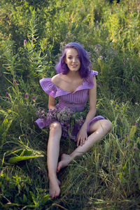 Teenage girl with dyed purple hair and a nose piercing in the grass with a bouquet of flowers