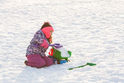 Rear view of girl with toy on snow