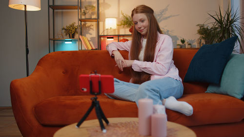 Young woman using laptop while sitting on sofa at home