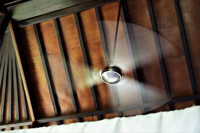 Low angle view of illuminated electric lamp on ceiling in building