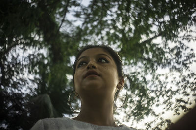 Low angle view of girl looking away against trees