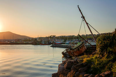 Sailboats moored on sea against clear sky during sunset