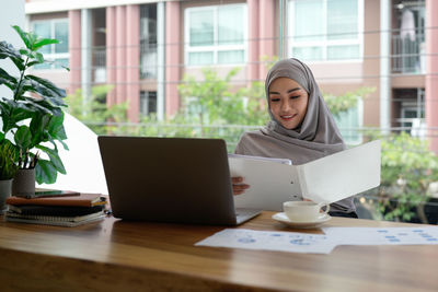 Young woman using laptop while sitting on table