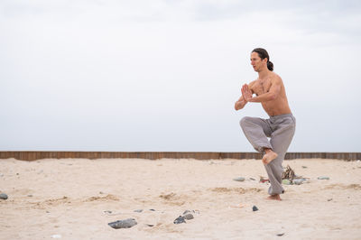 Full length of man jumping on beach against sky