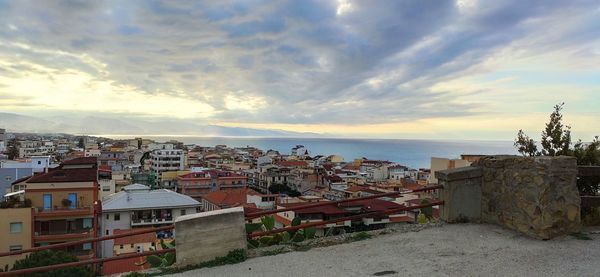 Houses by sea against sky during sunset