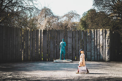 Woman walking on sculpture against trees