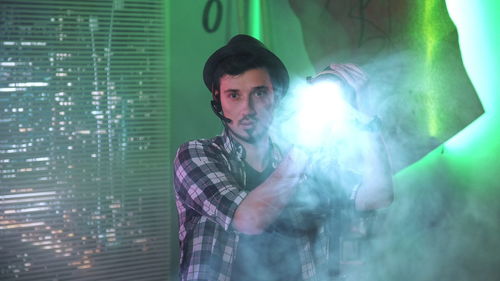 Man wearing hat holding spotlight standing in studio