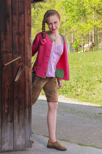 Portrait of smiling young woman standing by door