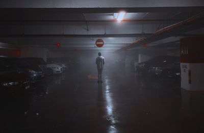 Man walking on illuminated road in city at night