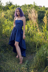 Teenage girl with dyed purple hair and a nose piercing in the grass