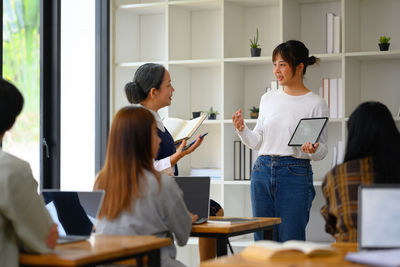 Side view of woman using digital tablet while sitting on table