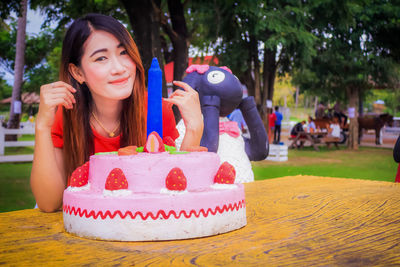 Portrait of smiling woman holding ice cream on table