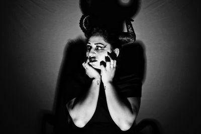 Woman in halloween costume looking away while sitting in darkroom